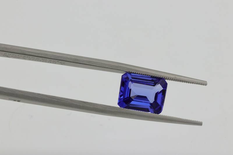 Cut violet-blue Tanzanite held in tweezers